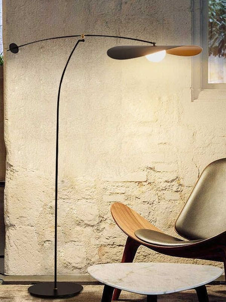 Alonso arc floor lamp illuminated over a reading chair