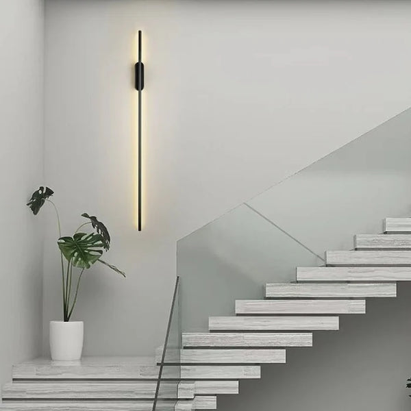 Linear black wall light illuminated in a bedroom